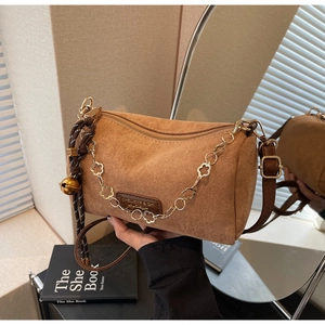 Dettaglio borsa a bauletto in pelle scamosciata marrone con catena dorata a fiori