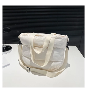 Gros plan d'un sac fourre-tout matelassé blanc avec bandoulière réglable sur bureau