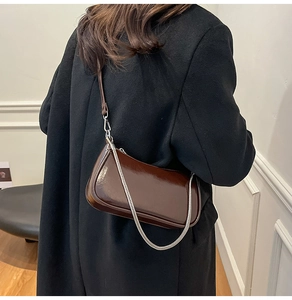 Detail der dunkelbraunen Lackleder-Baguette-Tasche mit Silberkette und langem Schultergurt