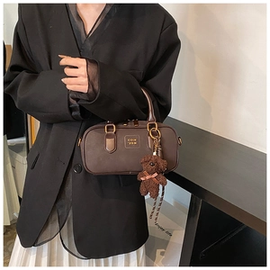Detailed view of brown PU leather bag with gold hardware and a cute plush bear charm