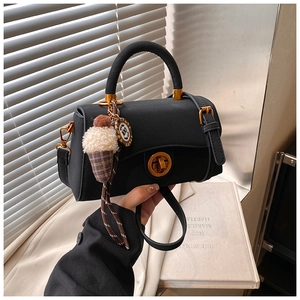 Nahaufnahme einer schwarzen Handtasche mit goldenem Drehverschluss und Plüschanhänger