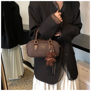 Detail view of coffee brown retro Boston bag with plush bear charm and handle straps