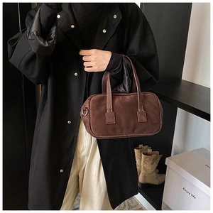 Detail of a dark brown matte textured handbag with silver D-rings and sturdy stitching