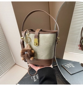 Detail of canvas bucket bag with leather trim and decorative plush monster charm