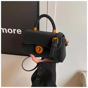 Detail der schwarzen matten Wildlederhandtasche mit goldenem Drehverschluss und Griff