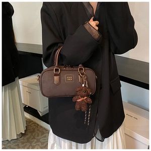 Detailed side view of vintage brown mini satchel bag with plush bear charm accessory