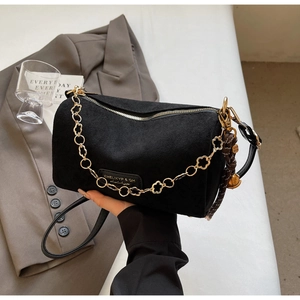 Dettaglio borsa a cilindro in camoscio nero con catena floreale dorata e logo