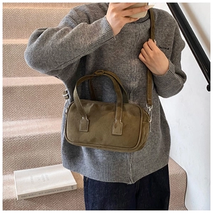 Close-up of olive green matte leather handbag with fine stitching and dual handle straps