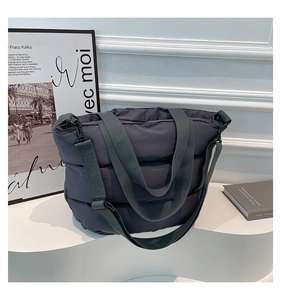 Sac cabas matelassé gris foncé avec bandoulière réglable dans un studio moderne et chic