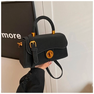 Detail der mattschwarzen Handtasche mit goldenem Verschluss und elegantem Griff