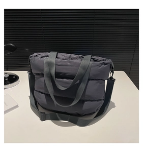 Détail d'un sac cabas en coton matelassé gris foncé avec bandoulière réglable amovible