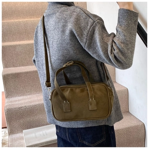 Olive green crossbody bag with visible contrast stitching and top handles shown on model