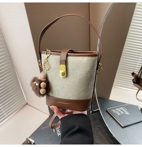 Detail of canvas bucket bag with leather trim and decorative plush charm accessory
