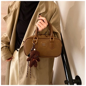 Detail of vintage brown leather Boston bag with plush bear charm and metallic hardware