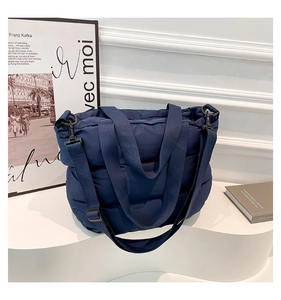 Vue détaillée du sac cabas matelassé bleu foncé avec bandoulière réglable et poignées