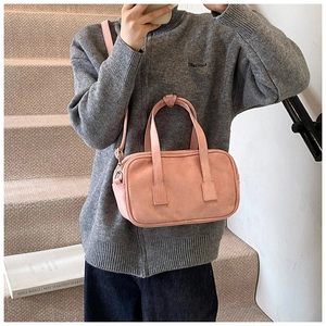 Detail of pink suede rectangular crossbody bag showing matte texture and dual top handles