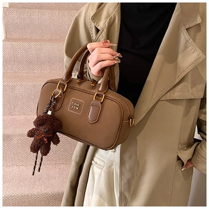 Detail of vintage dark brown Boston bag with plush bear charm and metallic brand logo