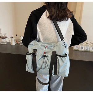 Dettaglio della borsa tote in nylon celeste con fibbia e coulisse sul modello