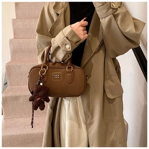 Brown Boston handbag detail with metal logo and cute teddy bear charm on faux leather