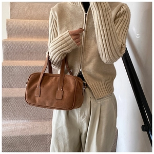 Detail of dark brown matte suede handbag with silver zipper and double handles