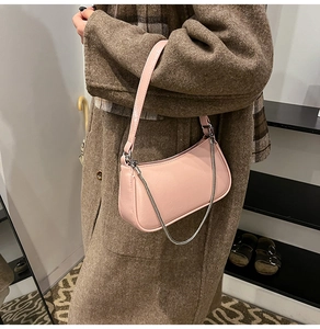 Nahaufnahme der rosa Baguette-Tasche aus Leder mit Silberkette an einem Model im Karomantel
