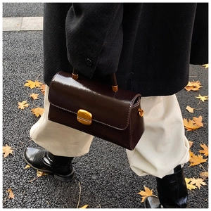 Borsa a tracolla vintage marrone cioccolato con fibbia dorata indossata dal modello