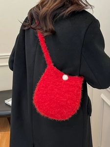 Chic red plush bucket bag with white pom-pom detail on black coat for women
