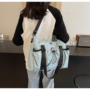 Dettaglio della borsa a tracolla azzurra con tasca laterale a coulisse e chiusura a fibbia