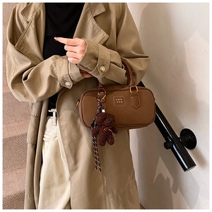 Detail of vintage brown PU leather Boston bag with plush bear charm and lettered logo