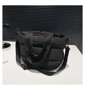 Détail du sac matelassé noir avec bandoulière réglable et doubles poignées courtes