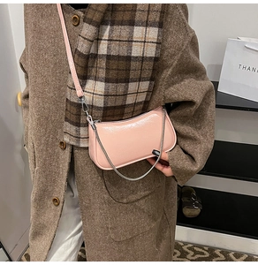 Detail der rosa glänzenden Achseltasche aus Lackleder mit silberner Kette und glattem Finish