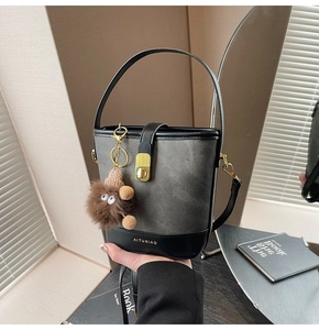 Detail of color-block canvas bucket bag with black leather trim and plush bear charm