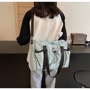 Foto lifestyle di una borsa a tracolla in nylon azzurro con strisce tricolore iconiche