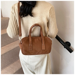 Close-up of caramel brown suede handbag featuring white contrast stitching details