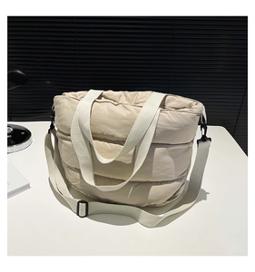 Détail du sac cabas matelassé avec larges anses blanches et texture en nylon crème