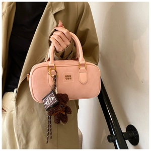 Detailed macro view of pink matte leather pillow bag with cute bear and mini book charms