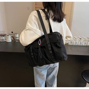 Dettaglio della borsa tote nera con tasca laterale con coulisse e etichetta colorata
