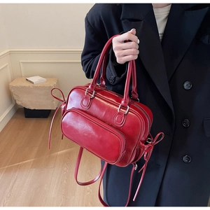 Detail of red glossy leather handbag with bow tie decoration and front zipper pocket