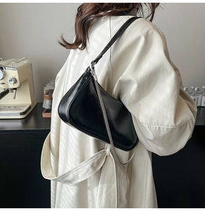 Detail der glänzenden schwarzen Achseltasche mit Silberkette, am Modell in Retro-Kulisse