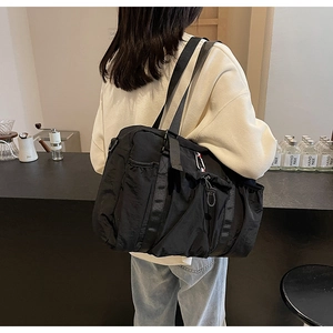 Dettaglio di una grande borsa tote in nylon nero con nastri decorativi sportivi tricolore