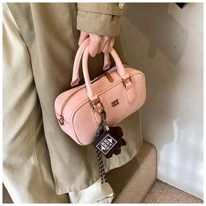Close-up of pink suede pillow bag with plush bear charm and holy bible pendant detail