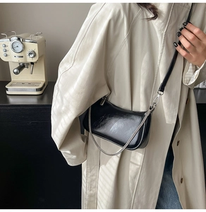 Detailansicht der schwarzen Lackleder-Achseltasche mit Silberkette und Lederriemen