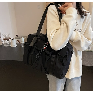 Grande borsa da viaggio in nylon nero con ciondolo tricolore in un caffè accogliente