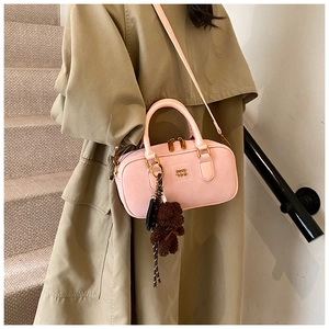 Pink Boston bag detail with plush bear charm and gold-tone hardware on khaki coat