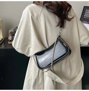 Detail einer schwarzen Lackleder-Schultertasche mit Silberkette und verstellbarem Lederriemen