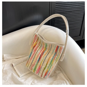 Detailaufnahme der bunt gestreiften Web-Tasche mit Ledergriff auf weißem Sofa