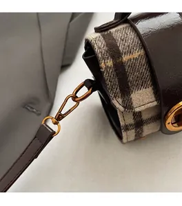 Dettaglio della mini borsa a quadri con chiusura dorata e finiture in pelle marrone