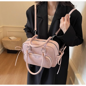 Pink matte leather crossbody bag with bow drawstring details and adjustable shoulder strap