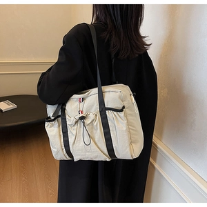 Dettaglio della grande borsa tote crema con tasca a coulisse e moschettone