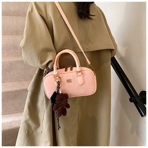 Detail of pink suede Boston bag with embossed logo and a cute brown plush bear charm